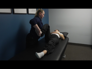 An osteopath performing hip testing on a patient.