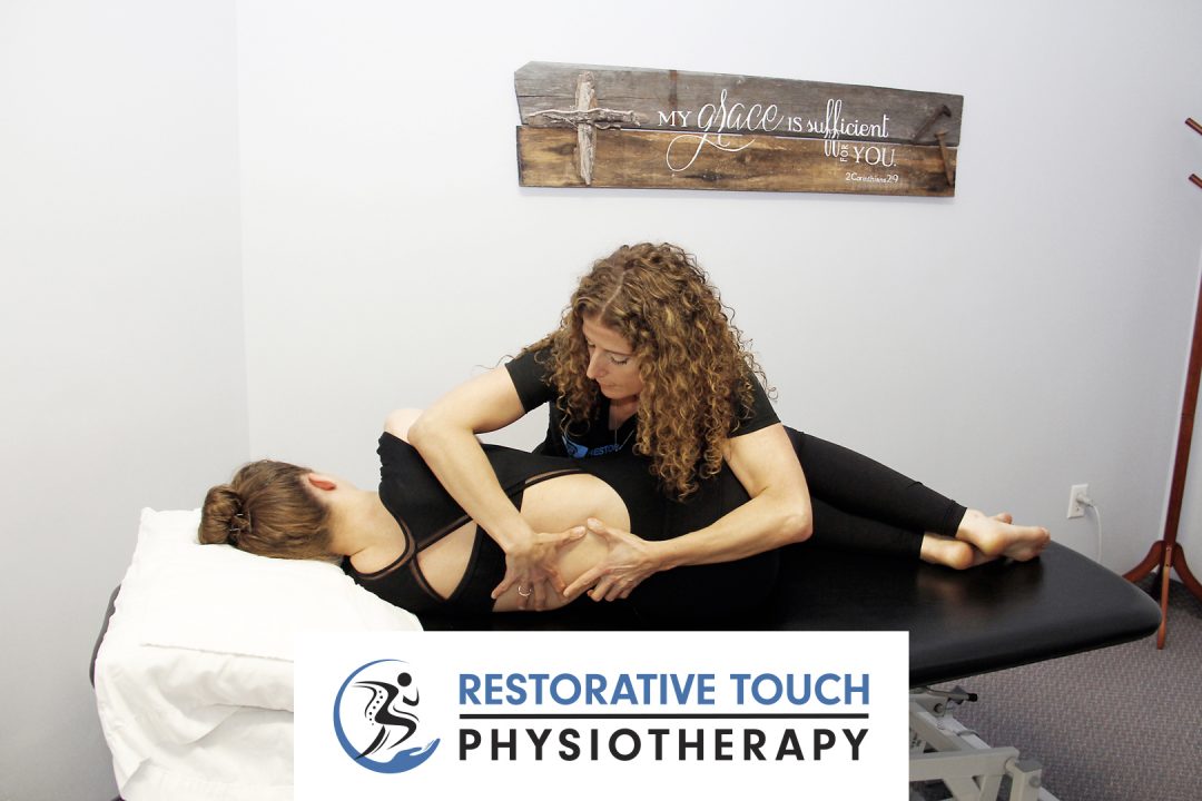 Marilena working on a patient's back while they are lying on their side on a table with the Restorative Touch Physiotherapy logo in the bottom center